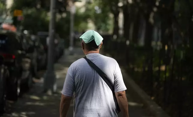 FILE - A man wears a damp towel on his head during a hot day in New York, Tuesday, July 16, 2024. (AP Photo/Seth Wenig, File)