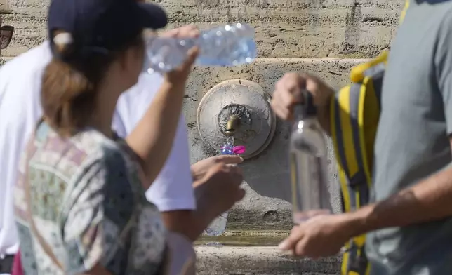 FILE - People queue at a fountain in St. Peter's Square on a hot day at the Vatican, Sunday, Aug. 11, 2024. (AP Photo/Gregorio Borgia, File)