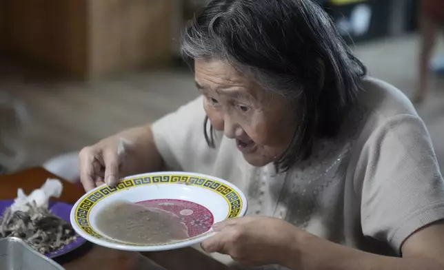 Marie Carl, 75, sits at the kitchen table at her home on Saturday, Aug. 17, 2024, in Mertarvik, Alaska. (AP Photo/Rick Bowmer)