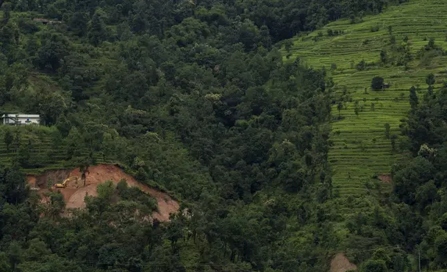 A worker uses an excavator to clear land for a road that would connect to the upper villages of Melamchi, northeast of Kathmandu, Nepal, on Sept. 15, 2024. (AP Photo/Niranjan Shrestha)