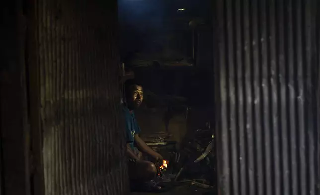 Sukuram Tamang, 50, prepares to cook food inside a temporary shelter on rented land in Melamchi, northeast of Kathmandu, Nepal, on Saturday, Sept. 14, 2024, after he lost his home in a landslide. (AP Photo/Niranjan Shrestha)