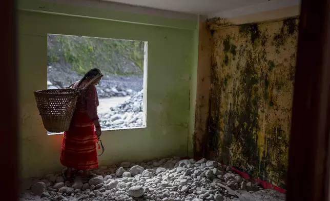 Sita Pandit, 50, walks in her house at Chanaute Market, Melamchi, northeast of Kathmandu, Nepal on Sunday, Sept. 15, 2024, that was damaged by floods in 2021. (AP Photo/Niranjan Shrestha)