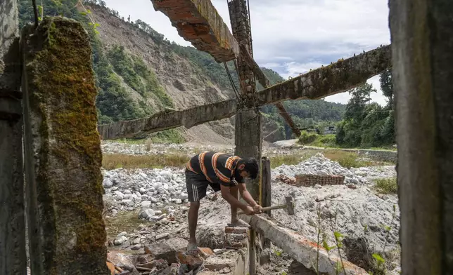 Saroj Lamichane salvages bricks from the ruins of his house northeast of Kathmandu, Nepal, Saturday, Sept. 14, 2024, that was destroyed by floods in 2021. (AP Photo/Niranjan Shrestha)