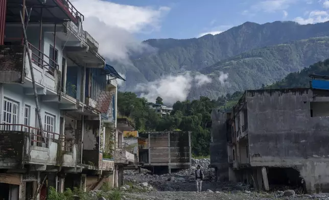 A man walks by abandoned houses in Chanaute Market, Melamchi, northeast of Kathmandu, Nepal, Sunday, Sept. 15, 2024, damaged by floods in 2021. (AP Photo/Niranjan Shrestha)