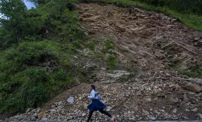 A girl runs in front of the recent landslide at Gyalthum, Melamchi, northeast of Kathmandu, Nepal, Sunday, Sept. 15, 2024. (AP Photo/Niranjan Shrestha)