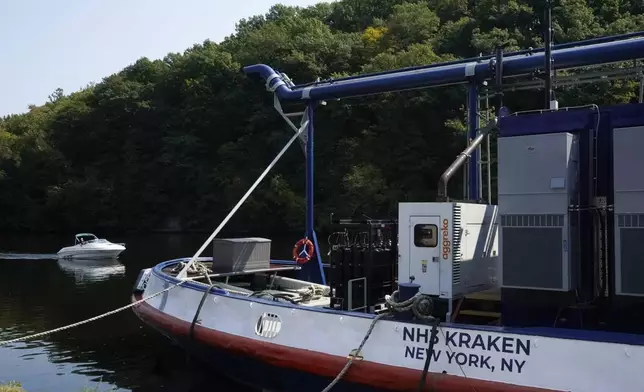 A boat, left, passes by the NH3 Kraken, a tugboat powered by ammonia, Friday, Sept. 13, 2024, in Kingston, N.Y. (AP Photo/Alyssa Goodman)