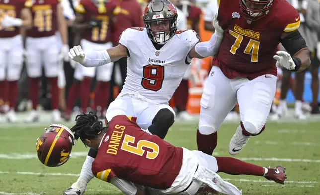 Washington Commanders quarterback Jayden Daniels (5) loses his helmet as he is hit by Tampa Bay Buccaneers linebacker Joe Tryon-Shoyinka (9) during the first half of an NFL football game Sunday, Sept. 8, 2024, in Tampa, Fla. (AP Photo/Jason Behnken)