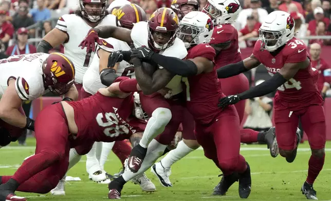 Washington Commanders running back Brian Robinson Jr., center, runs in for a touchdown as Arizona Cardinals linebacker Kyzir White (7) defends during the first half of an NFL football game, Sunday, Sept. 29, 2024, in Glendale, Ariz. (AP Photo/Rick Scuteri)