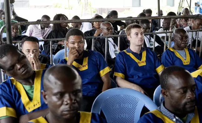 Back row, Tyler Thompson, 2nd left, Marcel Malanga, center, and Benjamin Reuben Zalman-Polun, 2nd right, all American citizens, attend a court verdict in Congo, Kinshasa, Friday Sept .13, 2024, on charges of taking part in a coup attempt in May 2024. (AP Photo/Samy Ntumba Shambuyi)