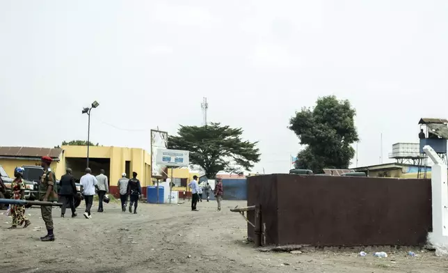 People walk past the Makala Central prison in Kinshasa, Congo, Tuesday, Sept. 3, 2024, after an attempted jailbreak in Congo’s main prison that left many people dead. (AP Photo/Samy Ntumba Shambuyi)