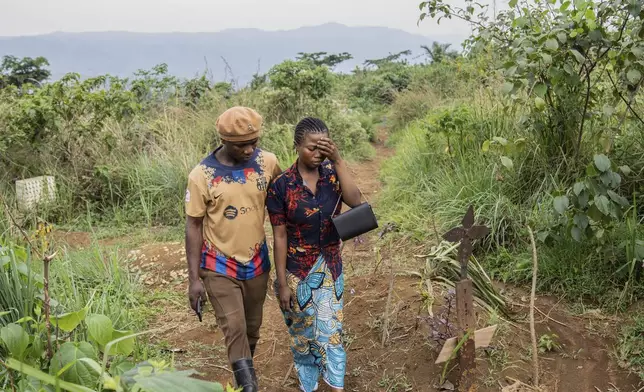 Olivier Lamec and Divine Wisoba walk by the grave of their daughter Maombi on Sept. 3, 2024. Maombi died of mpox, in Kamituga, South Kivu province, which is in eastern Congo and is the epicenter of the world’s latest outbreak of the disease. (AP Photo/Moses Sawasawa)