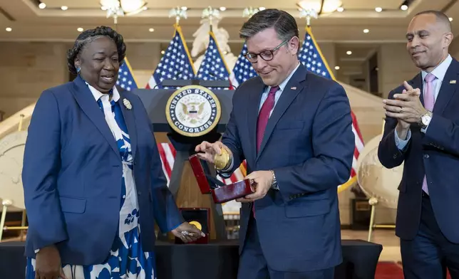 House Speaker Mike Johnson, R-La., reacts after dropping a Congressional Gold Medal while posing for a photograph with NASA's Johnson Space Center Senior Apollo Sample Processor and Lab Manager Andrea Mosie, left, at a Congressional Gold Medal ceremony to honor the Black women mathematicians of NASA who contributed to the space race and who were the subject of the book and movie "Hidden Figures," at the Capitol in Washington, Wednesday, Sept. 18, 2024. House Minority Leader Hakeem Jeffries, D-N.Y., watches at right. (AP Photo/J. Scott Applewhite)