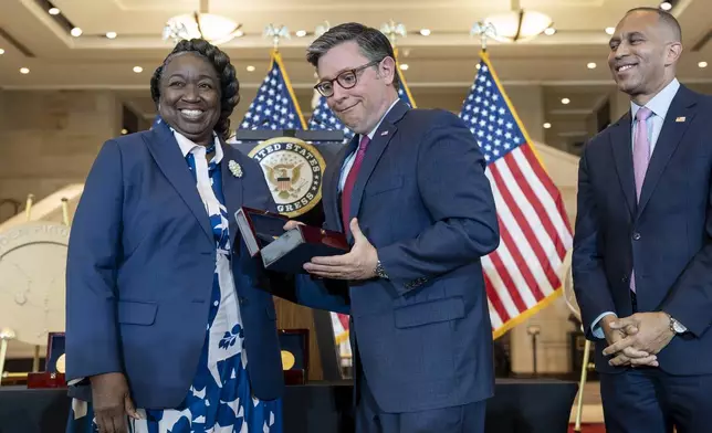 House Speaker Mike Johnson, R-La., reacts after dropping a Congressional Gold Medal while posing for a photograph with NASA's Johnson Space Center Senior Apollo Sample Processor and Lab Manager Andrea Mosie, left, at a Congressional Gold Medal ceremony to honor the Black women mathematicians of NASA who contributed to the space race and who were the subject of the book and movie "Hidden Figures," at the Capitol in Washington, Wednesday, Sept. 18, 2024. House Minority Leader Hakeem Jeffries, D-N.Y., watches at right. (AP Photo/J. Scott Applewhite)