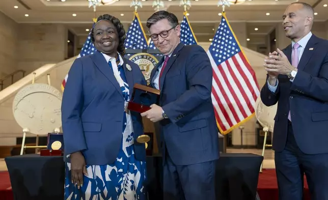 House Speaker Mike Johnson, R-La., accidentally drops a Congressional Gold Medal while posing for a photograph with NASA's Johnson Space Center Senior Apollo Sample Processor and Lab Manager Andrea Mosie, left, at a Congressional Gold Medal ceremony to honor the Black women mathematicians of NASA who contributed to the space race and who were the subject of the book and movie "Hidden Figures," at the Capitol in Washington, Wednesday, Sept. 18, 2024. House Minority Leader Hakeem Jeffries, D-N.Y., watches at right. (AP Photo/J. Scott Applewhite)