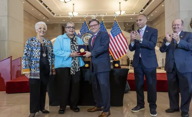 House Speaker Mike Johnson, R-La., center, presents a Congressional Gold Medal posthumously to Joylette Hylick, left, and Katherine Moore, daughters of Katherine Johnson, the Black NASA mathematician featured in the movie "Hidden Figures," at the Capitol in Washington, Wednesday, Sept. 18, 2024. They are joined by House Minority Leader Hakeem Jeffries, D-N.Y., second from right, and Sen. Chris Coons, D-Del. (AP Photo/J. Scott Applewhite)