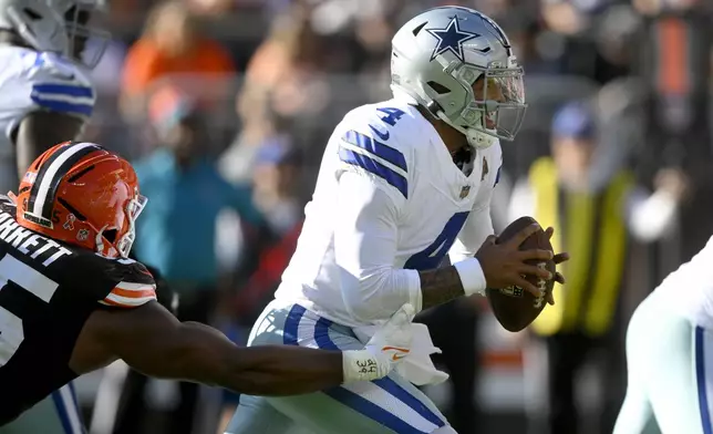 Dallas Cowboys quarterback Dak Prescott (4) scrambles away from pressure by Cleveland Browns defensive end Myles Garrett, left, in the first half of an NFL football game in Cleveland, Sunday, Sept. 8, 2024. (AP Photo/David Richard)