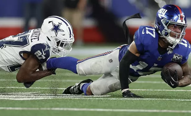 Dallas Cowboys cornerback Amani Oruwariye (27) pulls down New York Giants wide receiver Wan'Dale Robinson (17) during the fourth quarter of an NFL football game, Thursday, Sept. 26, 2024, in East Rutherford, N.J. (AP Photo/Adam Hunger)