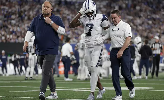 Dallas Cowboys cornerback Trevon Diggs (7) walks off the field with trainers during the third quarter of an NFL football game against the New York Giants, Thursday, Sept. 26, 2024, in East Rutherford, N.J. (AP Photo/Adam Hunger)