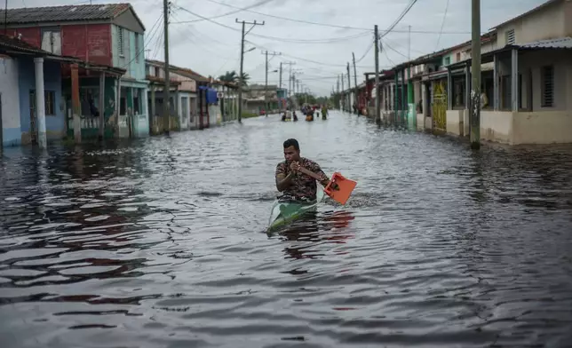 A man in a kayak uses a makeshift paddle as he travels through a street flooded in the passing of Hurricane Helene, in Batabano, Mayabeque province, Cuba, Thursday, Sept. 26, 2024. (AP Photo/Ramon Espinosa)