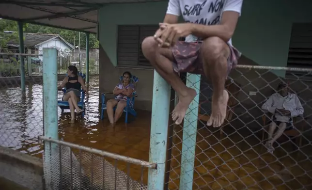 People lounge on a flooded porch after the passage of Hurricane Helene in Guanimar, Artemisa province, Cuba, Wednesday, Sept. 25, 2024. (AP Photo/Ramon Espinosa)