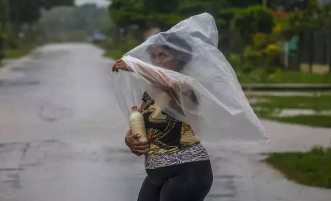 A resident uses a piece of plastic sheet as protection from heavy rains brought on by Hurricane Helene, in Batabano, Cuba, Wednesday, Sept. 25, 2024. (AP Photo/Ramon Espinosa)