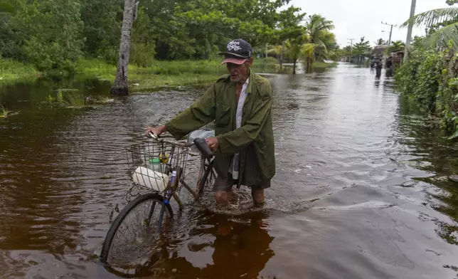 A man pushes his bicycle through a flooded street after Hurricane Helene passed through Guanimar, Artemisa province, Cuba, Wednesday, Sept. 25, 2024. (AP Photo/Ramon Espinosa)