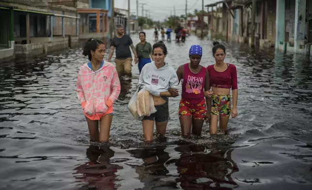 Residents wade through a street flooded in the passing of Hurricane Helene, in Batabano, Mayabeque province, Cuba, Thursday, Sept. 26, 2024. (AP Photo/Ramon Espinosa)