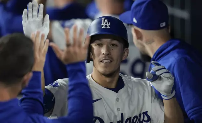 Los Angeles Dodgers' Tommy Edman, left, celebrates in the dugout after hitting a home run during the eighth inning of a baseball game against the Chicago Cubs in Los Angeles, Wednesday, Sept. 11, 2024. Teoscar Hernández also scored. (AP Photo/Ashley Landis)