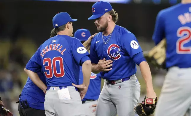 Chicago Cubs relief pitcher Porter Hodge, right, grabs his chest as manager Craig Counsell, left, and a trainer check on him during the ninth inning of a baseball game against the Los Angeles Dodgers, Tuesday, Sept. 10, 2024, in Los Angeles. (AP Photo/Mark J. Terrill)