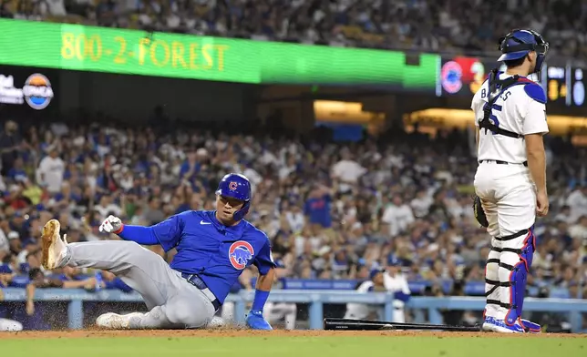 Chicago Cubs' Seiya Suzuki, left, scores on a an error by Los Angeles Dodgers second baseman Kiké Hernández as Los Angeles Dodgers catcher Austin Barnes stands by during the eighth inning of a baseball game, Tuesday, Sept. 10, 2024, in Los Angeles. (AP Photo/Mark J. Terrill)