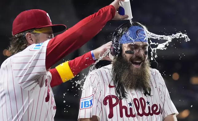 Philadelphia Phillies' Brandon Marsh, right, is doused by Bryson Stott after the Phillies won a baseball game against the Chicago Cubs, Wednesday, Sept. 25, 2024, in Philadelphia. (AP Photo/Matt Slocum)