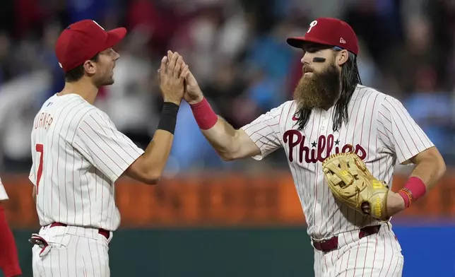 Philadelphia Phillies' Brandon Marsh, right, and Trea Turner celebrate after the Phillies won a baseball game against the Chicago Cubs, Wednesday, Sept. 25, 2024, in Philadelphia. (AP Photo/Matt Slocum)