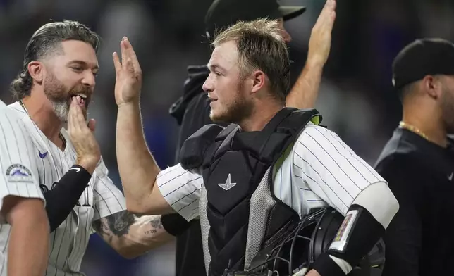 Colorado Rockies catcher Hunter Goodman, front right, is congratulated by Jake Cave, left, after their victory over the Chicago Cubs in a baseball game Friday, Sept. 13, 2024, in Denver. (AP Photo/David Zalubowski)