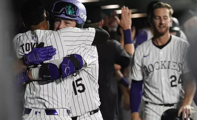 Colorado Rockies' Ezequiel Tovar, left, hugs Hunter Goodman (15) who returns to the dugout after hitting a grand slam off Chicago Cubs relief pitcher Nate Pearson in the eighth inning of a baseball game Friday, Sept. 13, 2024, in Denver. (AP Photo/David Zalubowski)