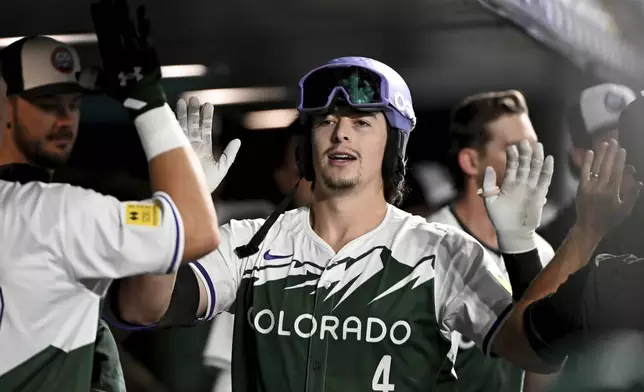 Colorado Rockies' Michael Toglia, center, celebrates with teammates after hitting a one-run home run in the seventh inning of a baseball game against the Chicago Cubs, Saturday, Sept. 14, 2024, in Denver. (AP Photo/Geneva Heffernan)