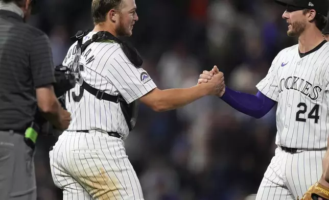 Colorado Rockies third baseman Ryan McMahon, right, congratulates catcher Hunter Goodman after the Rockies victory over the Chicago Cubs in a baseball game, Friday, Sept. 13, 2024, in Denver. (AP Photo/David Zalubowski)