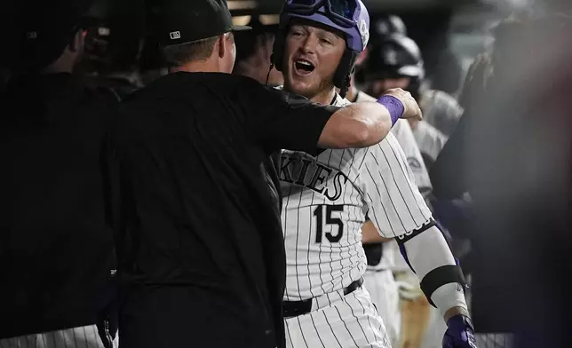 Colorado Rockies' Hunter Goodman, right, is congratulated as he returns to the dugout after hitting a grand slam off Chicago Cubs relief pitcher Nate Pearson in the eighth inning of a baseball game Friday, Sept. 13, 2024, in Denver. (AP Photo/David Zalubowski)