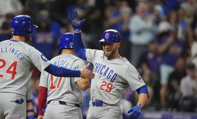 Chicago Cubs' Cody Bellinger, left, congratulates Michael Busch (29) who crosses home plate after hitting a three-run home run off Colorado Rockies relief pitcher Victor Vodnik in the eighth inning of a baseball game Friday, Sept. 13, 2024, in Denver. (AP Photo/David Zalubowski)