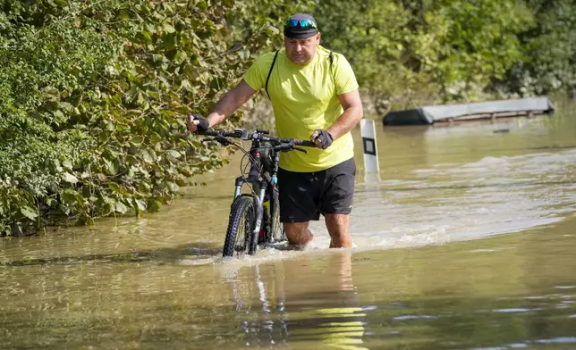 A cyclist pushes his bicycle through a flooded street in Bohumin, Czech Republic, Tuesday, Sept. 17, 2024. (AP Photo/Darko Bandic)