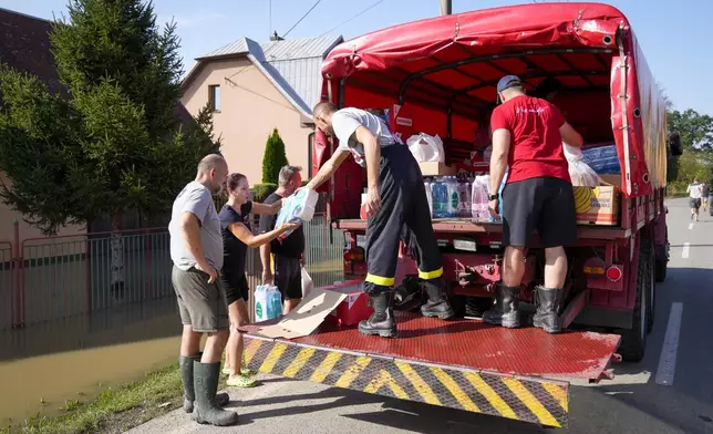 Firemen deliver aid to residents whose homes are flooded in Bohumin, Czech Republic, Tuesday, Sept. 17, 2024. (AP Photo/Darko Bandic)