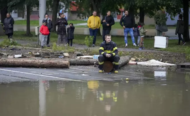 A fireman and residents look at flooding waters in Ostrava, Czech Republic, Monday, Sept. 16, 2024. (AP Photo/Darko Bandic)