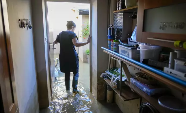 Zuzana Kublova wades through her flooded family home, in Bohumin, Czech Republic, Tuesday, Sept. 17, 2024. (AP Photo/Darko Bandic)