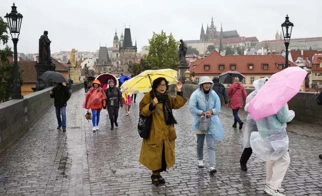 People with umbrellas against the rain as they cross the medieval Charles Bridge in Prague, Czech Republic, Friday, Sept. 13, 2024. (AP Photo/Petr David Josek)