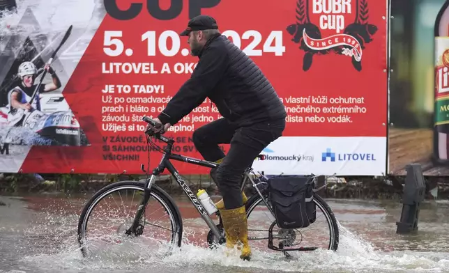 A resident rides a bicycle through a flooded street in Litovel, Czech Republic, Monday, Sept. 16, 2024. (AP Photo/Petr David Josek)