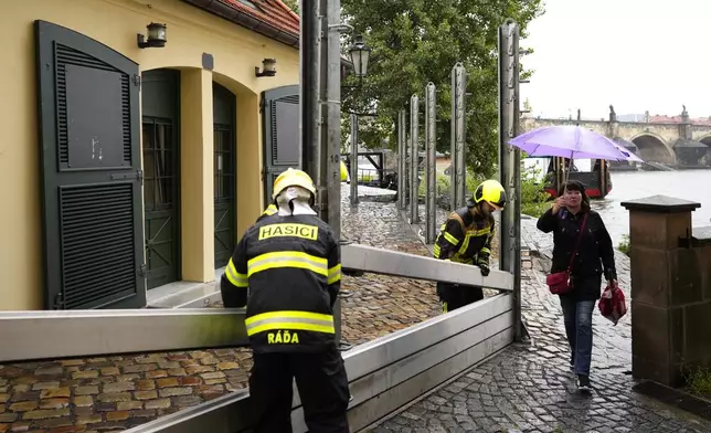 Firefighters adjust parts of the anti-flood barriers in Prague, Czech Republic, Friday, Sept. 13, 2024. (AP Photo/Petr David Josek)