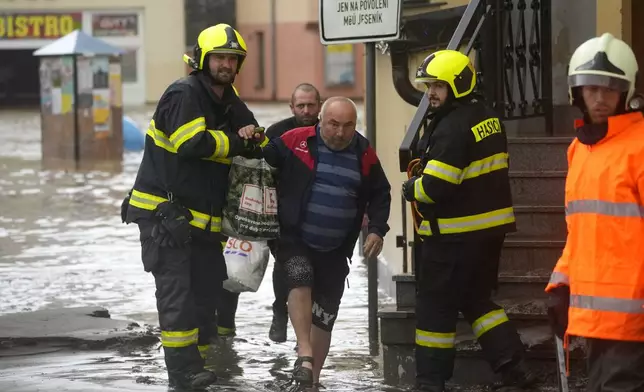 Firemen help a resident during floods in Jesenik, Czech Republic, Sunday, Sept. 15, 2024. (AP Photo/Petr David Josek)