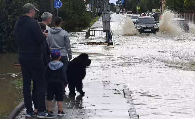 A group of people stand next to a flooded street in Opava, Czech Republic, Sunday Sept. 15, 2024. (Jaroslav Ozana/CTK via AP)