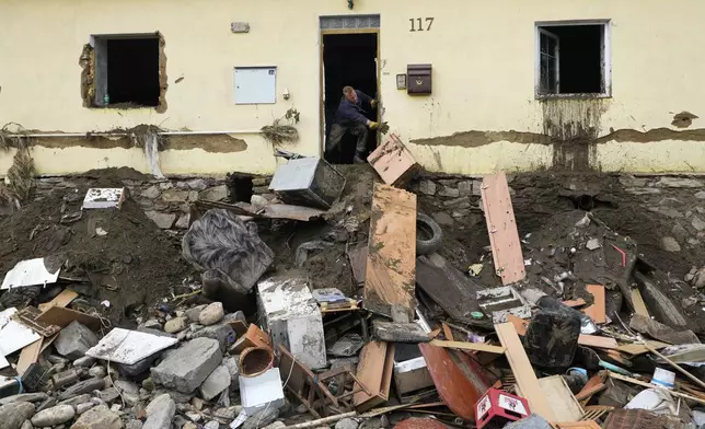 A man throws damaged goods and furniture off a house as residents return to clean up after recent floods in Mikulovice, Czech Republic, Thursday, Sept. 19, 2024. (AP Photo/Petr David Josek)