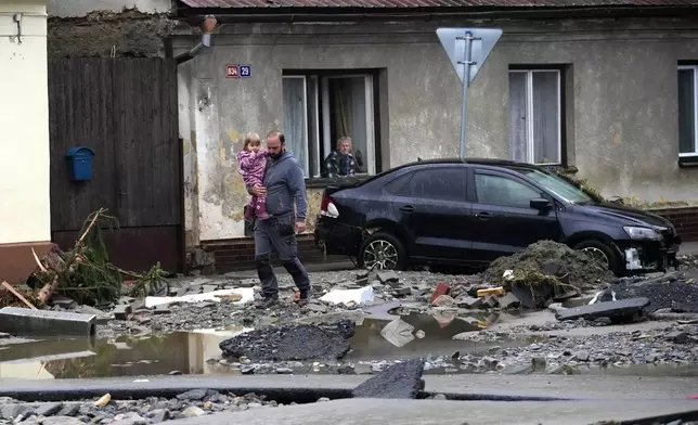 Residents walk through debris after recent floods in Jesenik, Czech Republic, Monday, Sept. 16, 2024. (AP Photo/Petr David Josek)