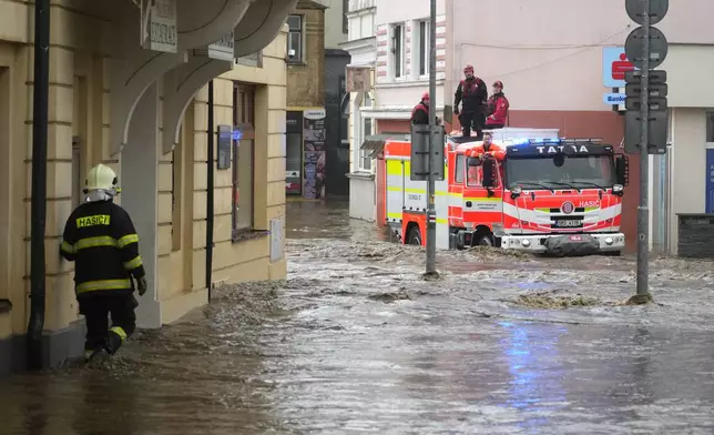 A fireman walks to a house through a flooded street in Jesenik, Czech Republic, Sunday, Sept. 15, 2024. (AP Photo/Petr David Josek)